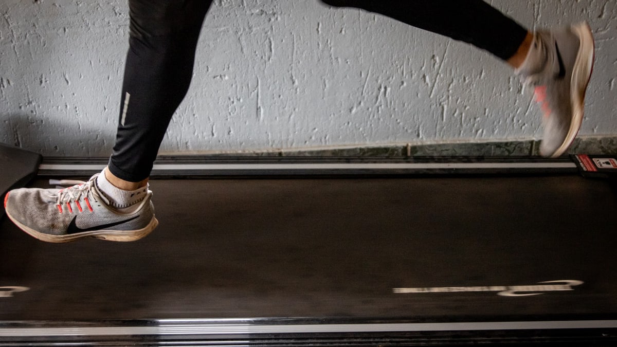 Close-up of a woman's legs running on a treadmill indoors, focusing on fitness and exercise.